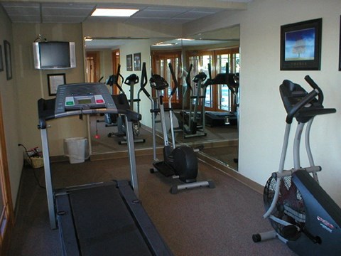 A gym with treadmills, exercise bikes and a television.