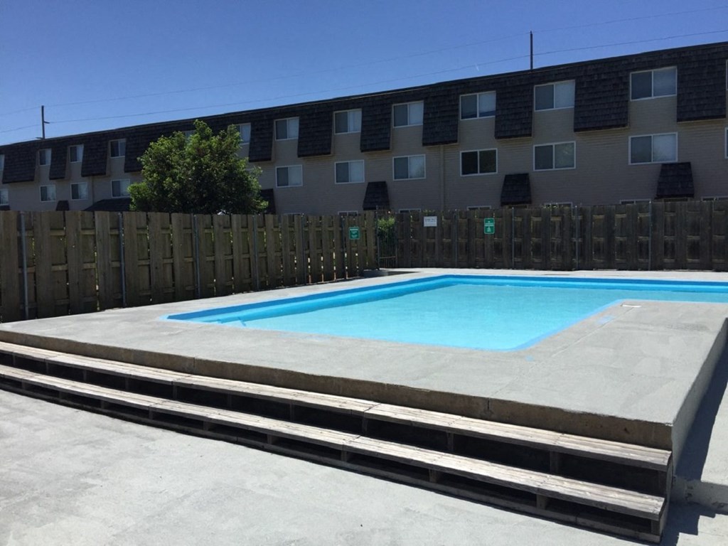 A refreshing swimming pool surrounded by lounge chairs at Cedar Ridge Apartments.
