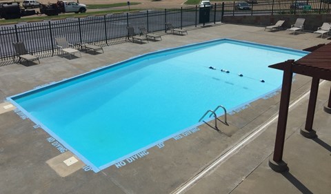 A rectangular pool with a blue tinted water and a black fence surrounding it.