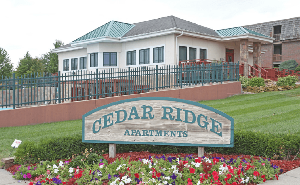 Cedar Ridge Apartments - Welcome Signage The welcome sign at Cedar Ridge Apartments, set against a green landscape.