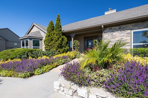 A house with a stone wall and a garden in front.