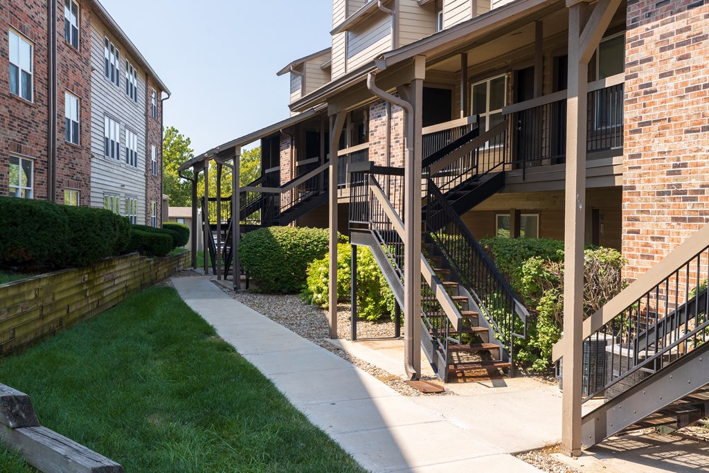 A charming apartment exterior with balconies and neatly trimmed bushes.