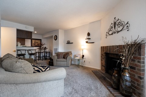A living room with a grey couch and a fireplace.