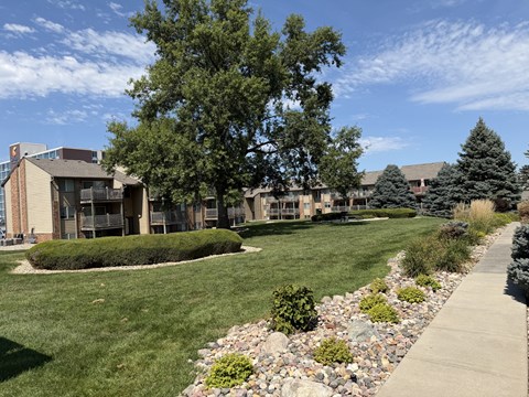Fox Run Apartments in Omaha, Nebraska near a grassy area with a stone walking path and mature tree