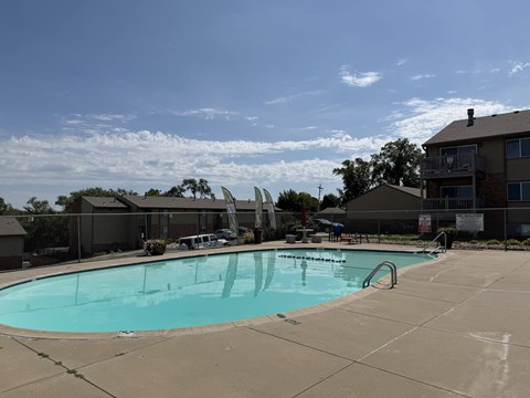 A large swimming pool with a slide and a building in the background.