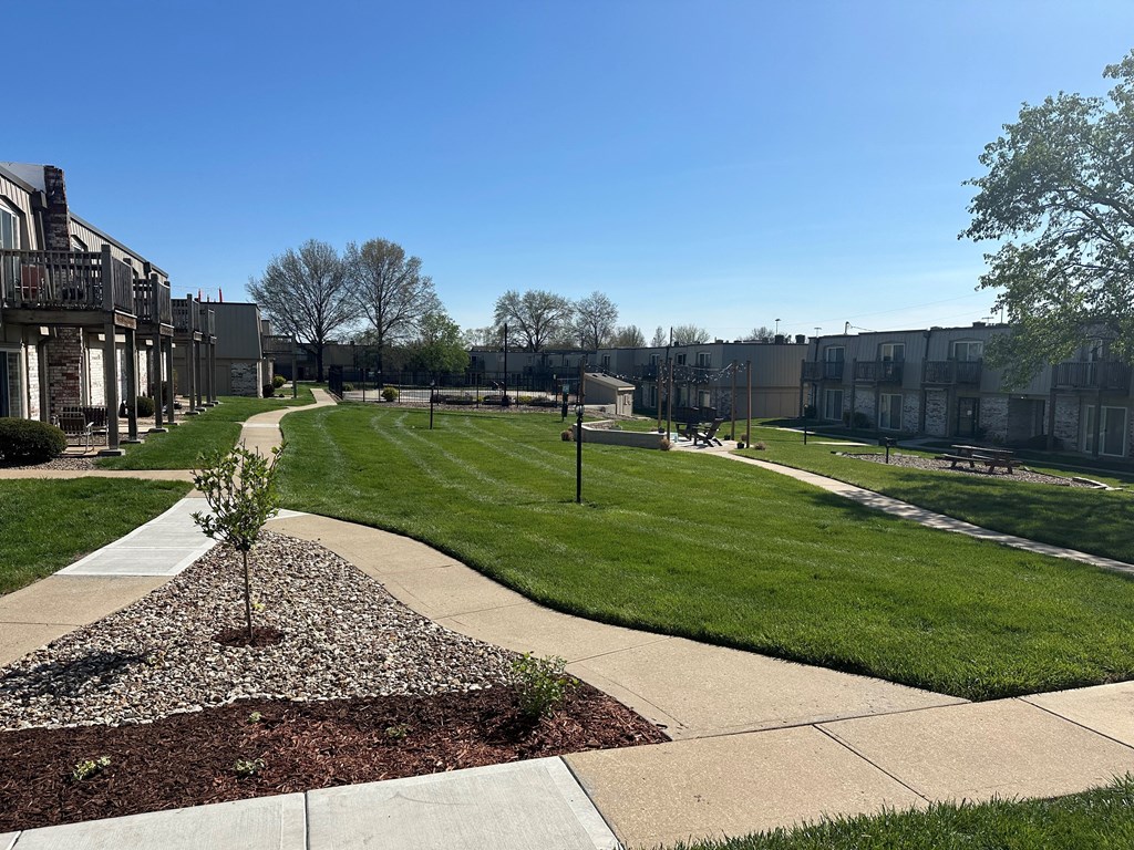 A park in the center of the Park 25 Apartments complex, featuring green lawns and walkways surrounded by apartment buildings.
