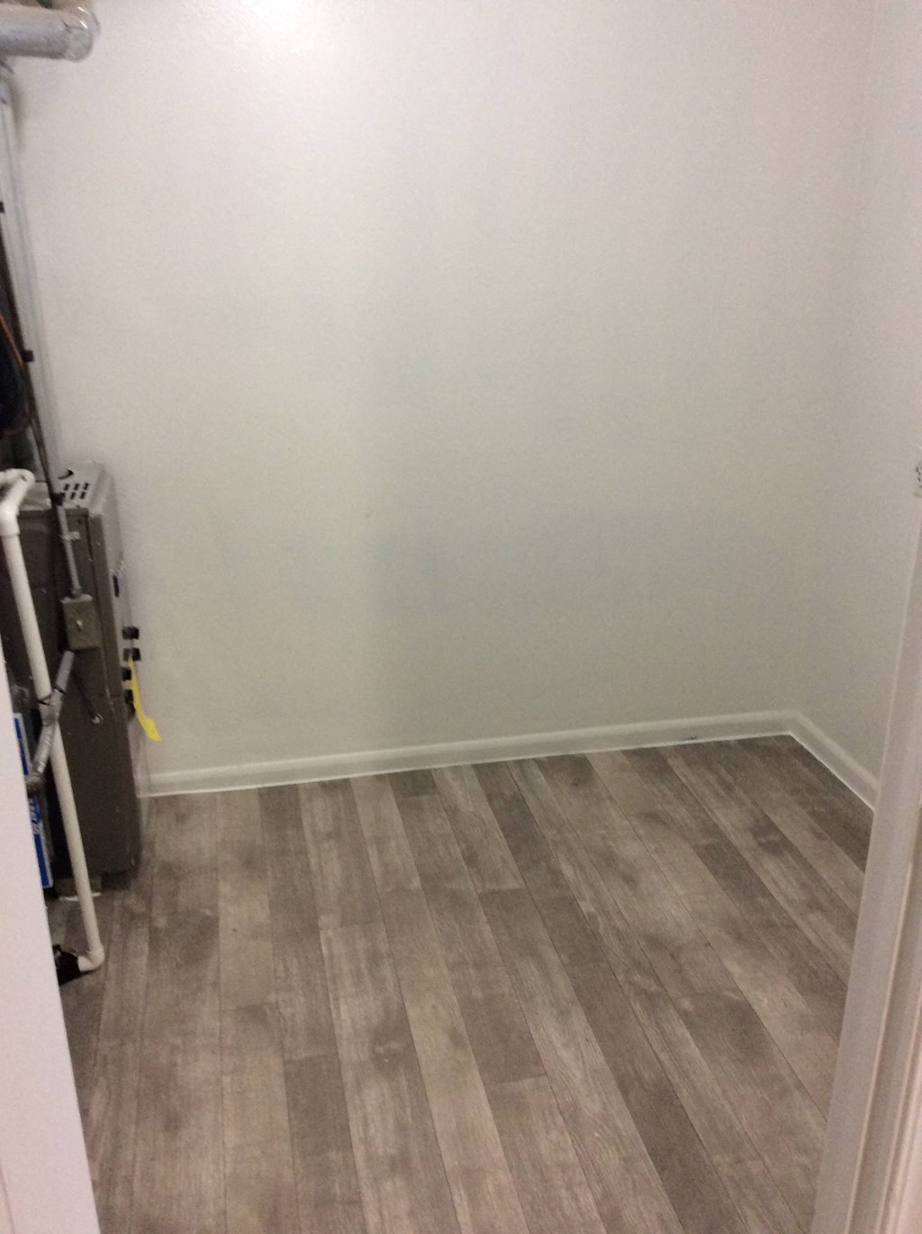 Utility/furnace closet in the Yeakel Townhome, featuring a wooden floor and white walls.