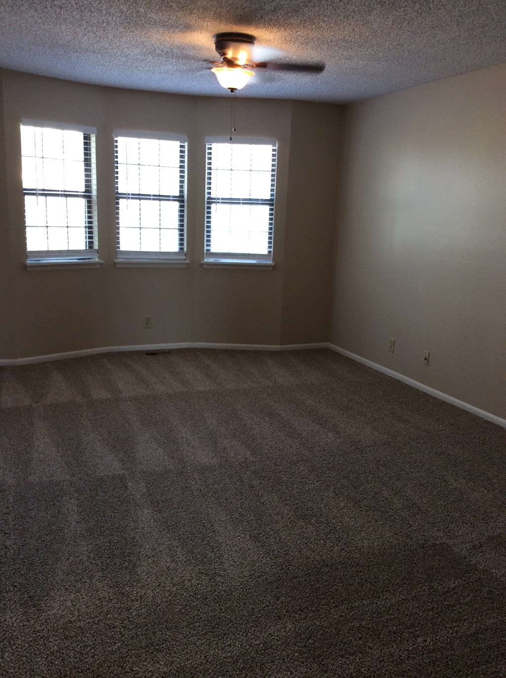 Living room in the Yeakel Townhome, featuring a carpeted floor and a window with blinds.