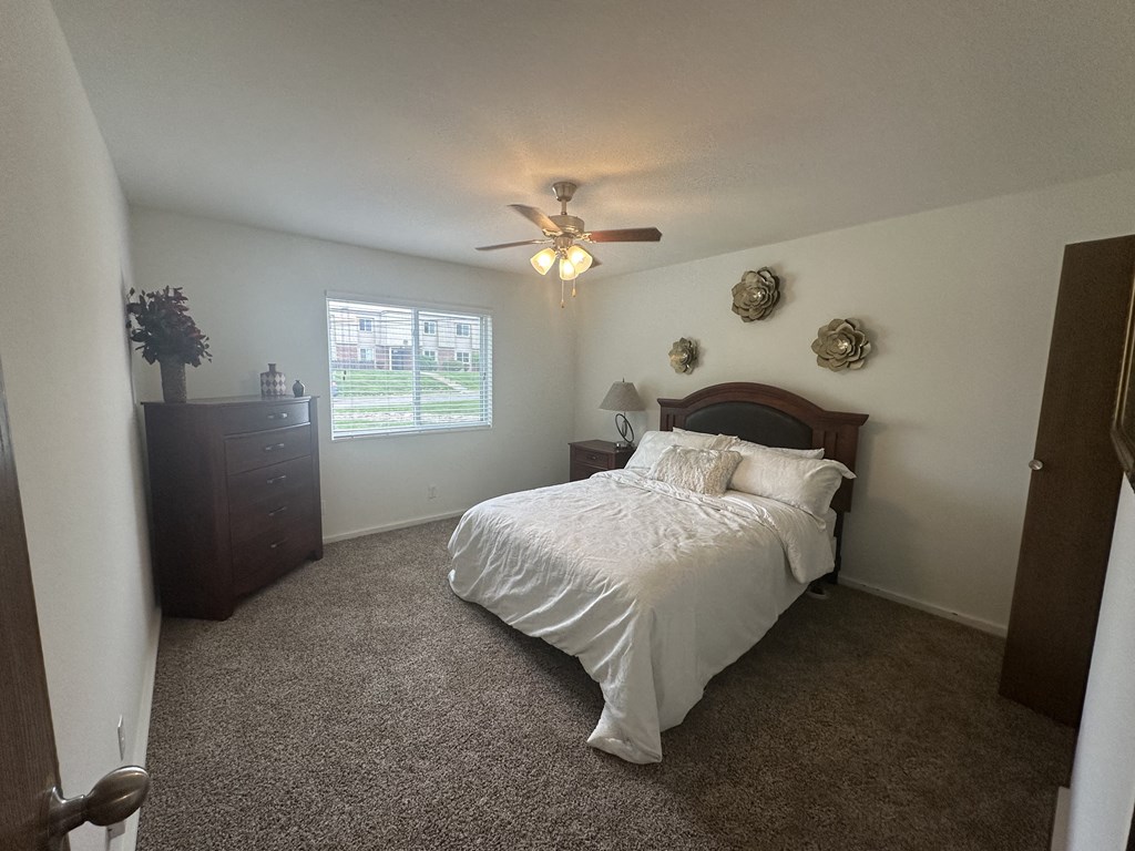 A bedroom in a Park 25 Apartments model unit, featuring a bed and a ceiling fan, creating a comfortable and relaxing space.