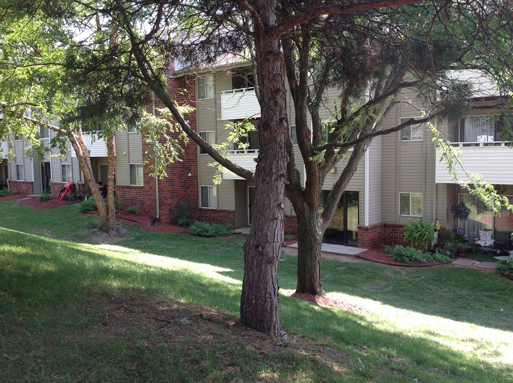 Scenic side view of an apartment building with lush green trees in the Muirfield Apartments complex.