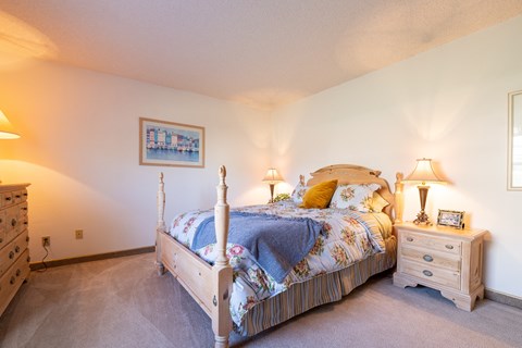 A bedroom with a bed, nightstand, and lamp.