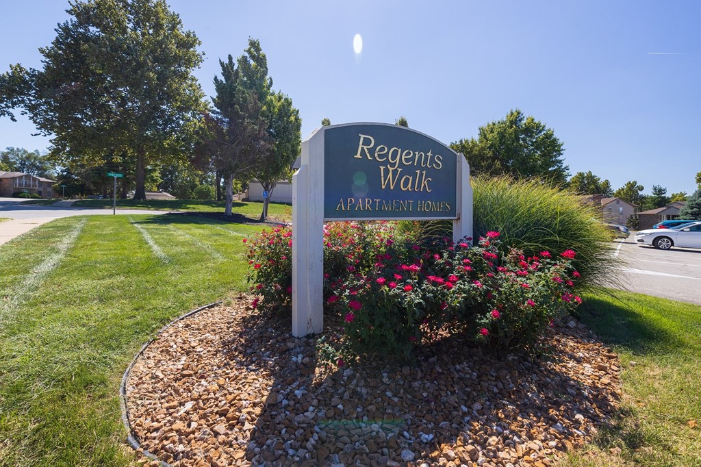 The entrance sign for Regent’s Walk Apartment Homes, set against a landscaped backdrop with flowers and greenery.