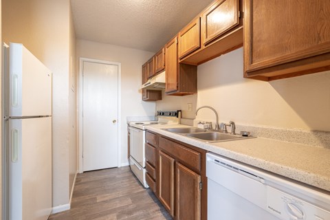 redesigned kitchen with white appliances and wood cabinets in an apartment