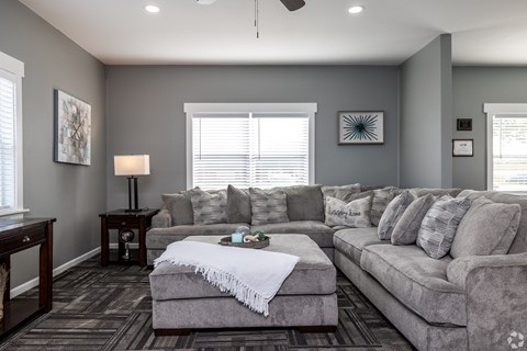 A living room with a grey couch and a white throw blanket on it.