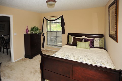 A bedroom with a bed, dresser, and window.