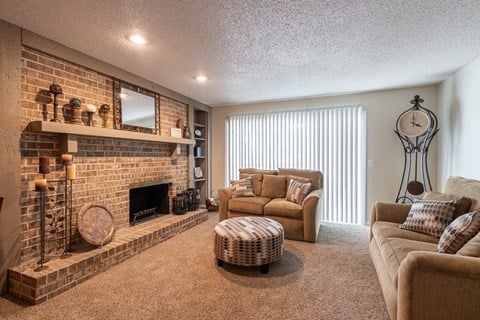 a living room with a brick fireplace and couches