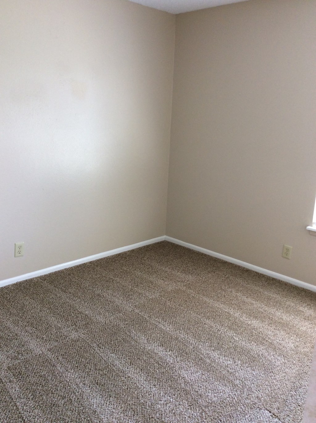 Upper bedroom in the Yeakel Townhome, featuring a carpeted floor and white baseboards.