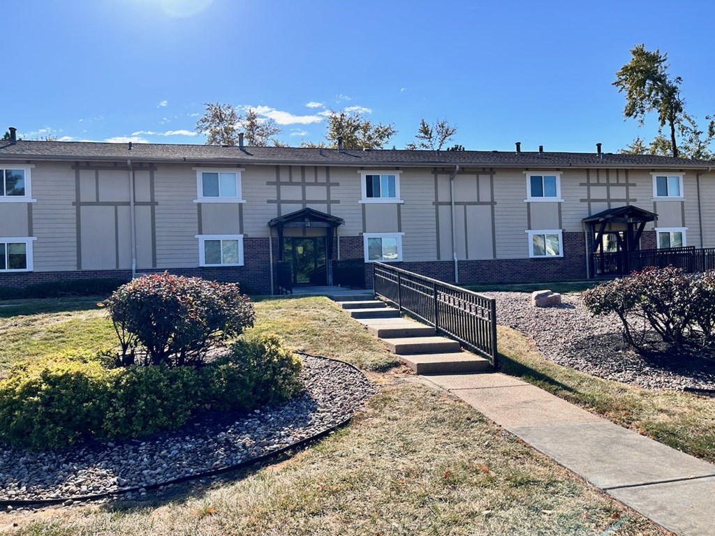 Exterior of an apartment building at Cambridge Apartments, with a sidewalk in front of the building.