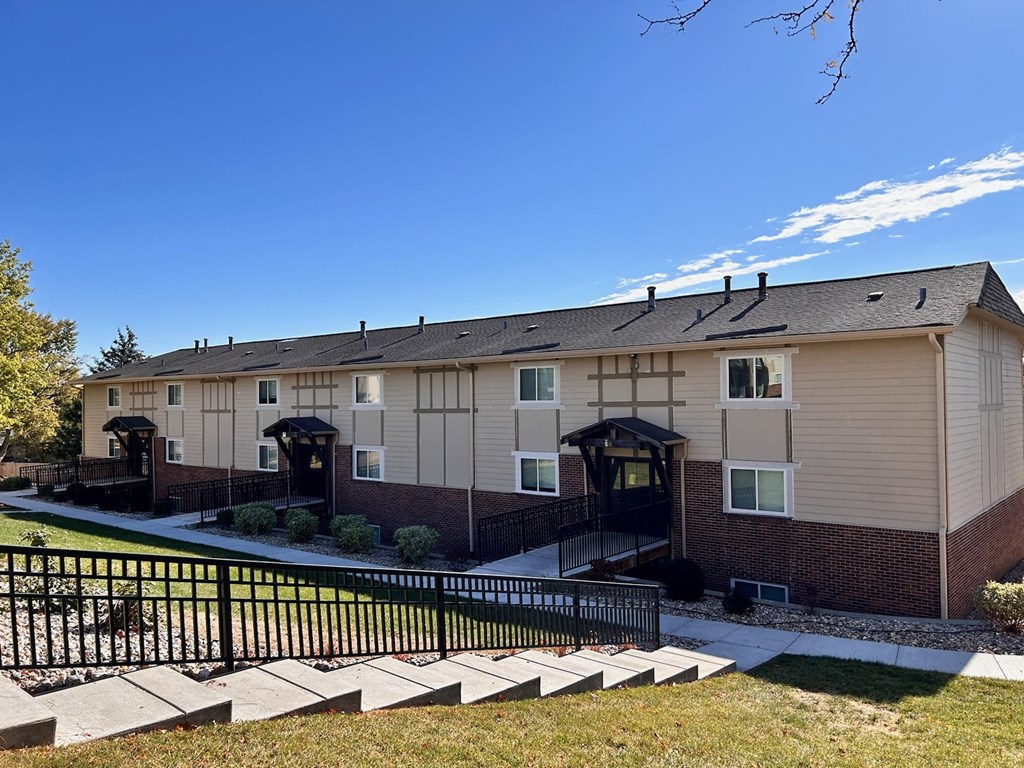Apartment building at Cambridge Apartments with a yard and black wrought iron stair railings.