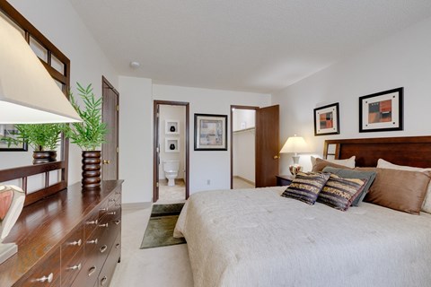 Regency Woods model unit bedroom featuring a large bed and a wooden dresser.