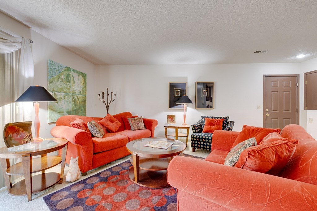 a living room with orange couches and chairs and a rug