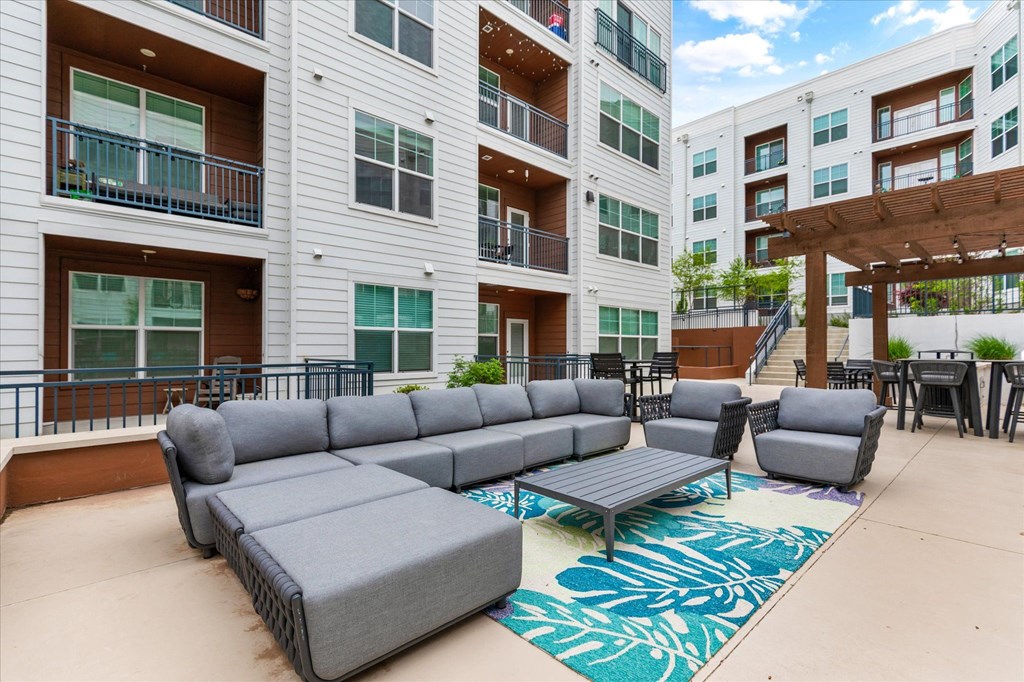 a patio with couches and tables in front of an apartment building
