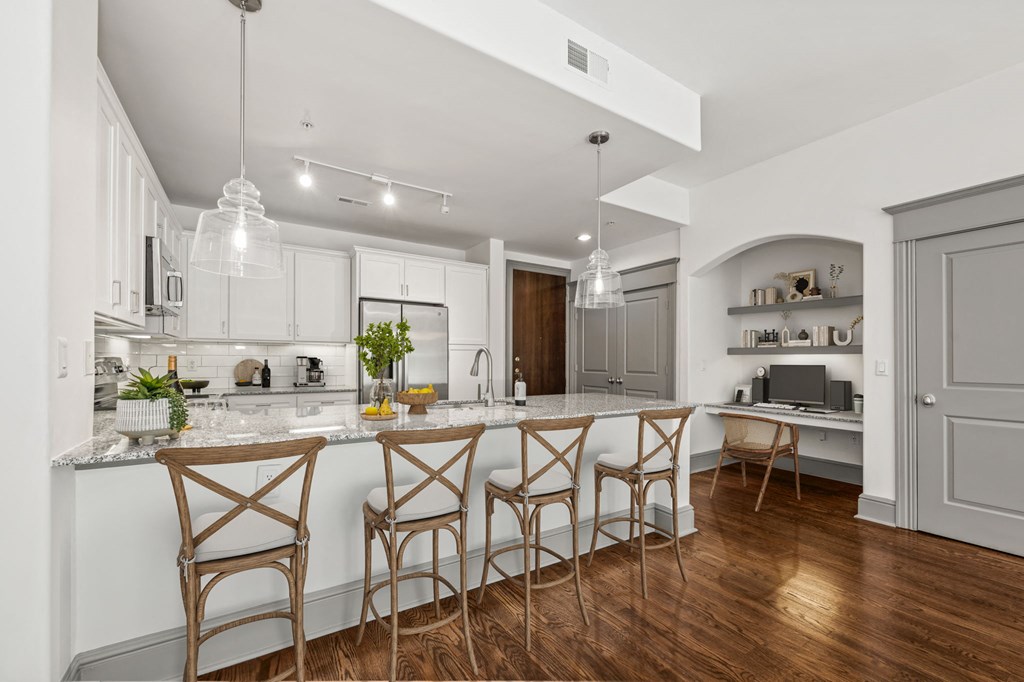 a kitchen with white cabinets and a marble counter top