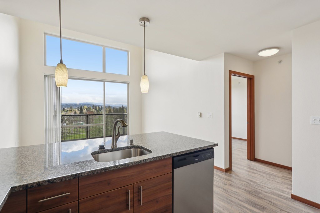 A kitchen with a sink and a window overlooking a field.