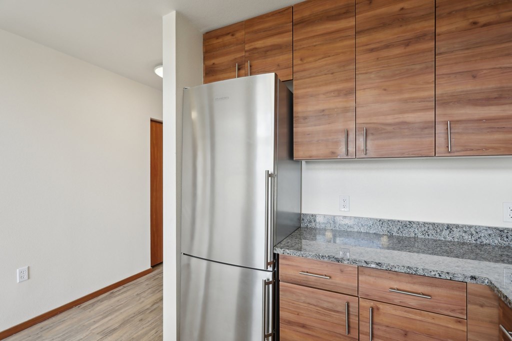 A kitchen with a refrigerator and wooden cabinets.