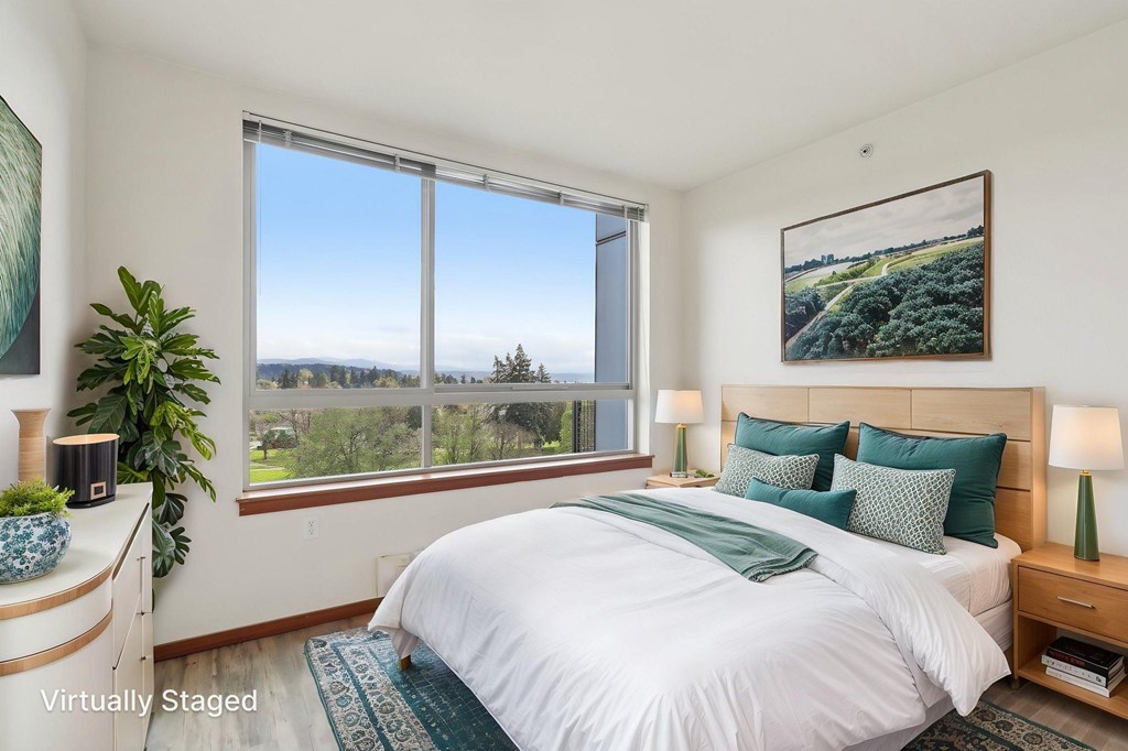 A bedroom with a large bed and a view of the outdoors through a large window.
