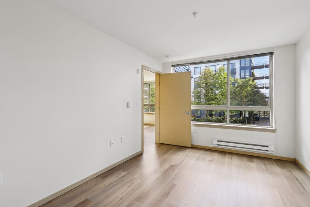A room with a wooden floor and a door leading to a balcony.