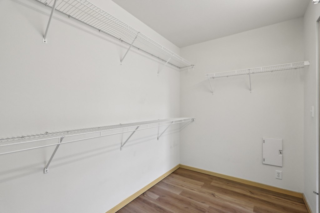 A room with white walls and wooden flooring with three metal racks on the wall.