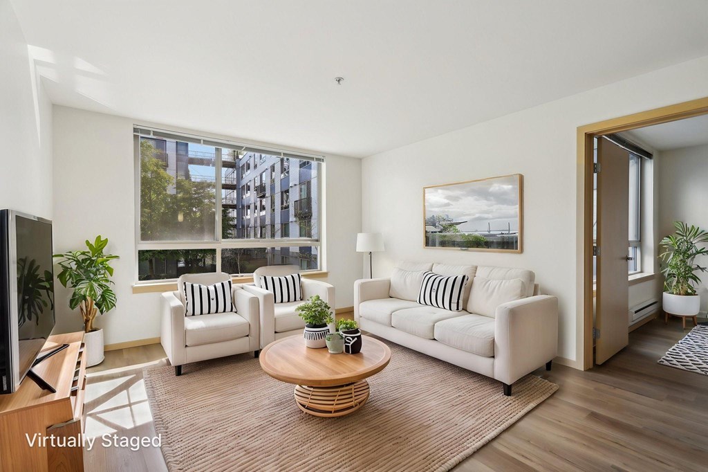 A living room with a white couch, a coffee table, and a painting on the wall.
