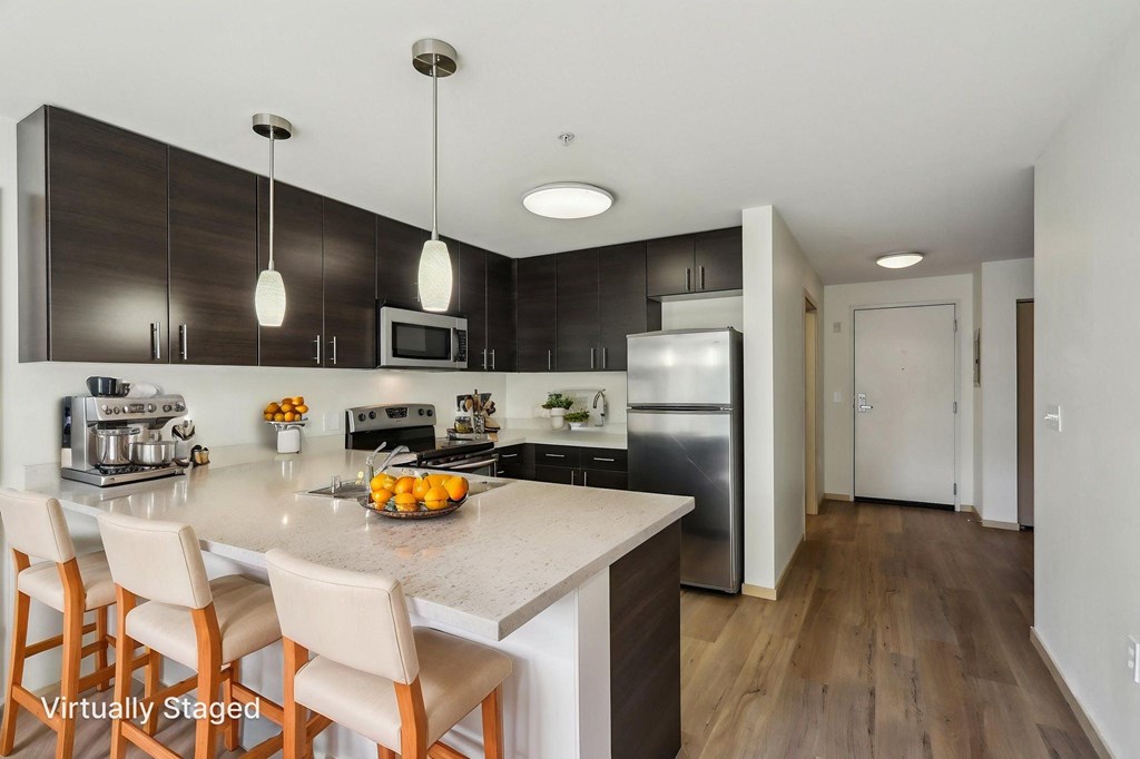A kitchen with a counter and chairs.
