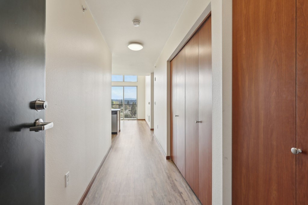 A long hallway with wood floors and white walls.
