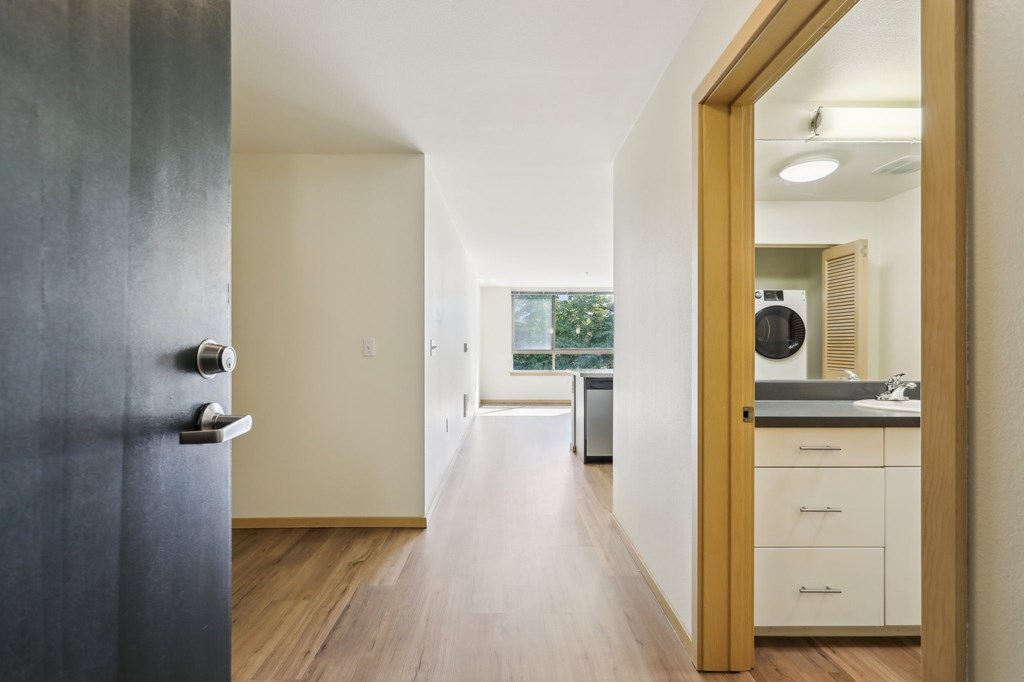 A modern kitchen with white cabinets and a wooden floor.
