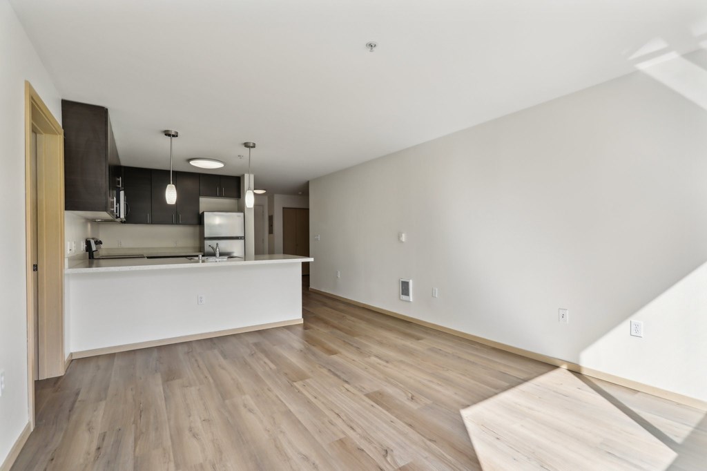 A kitchen with a white countertop and wooden flooring.