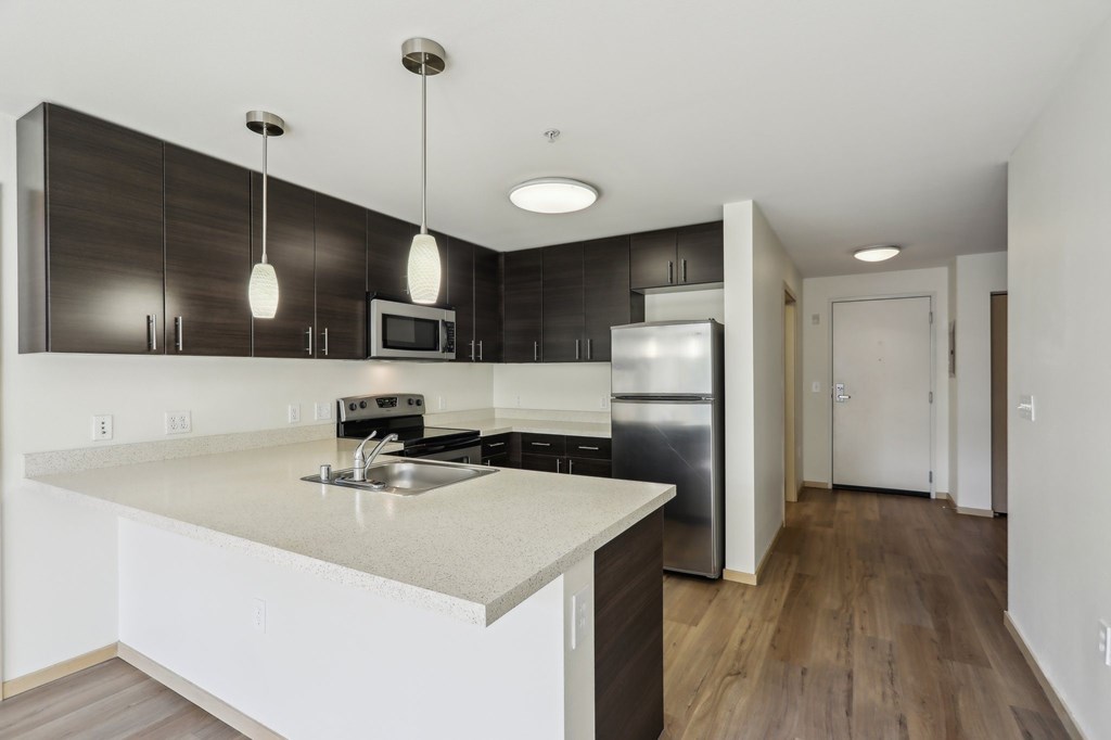 A modern kitchen with a white countertop and stainless steel appliances.