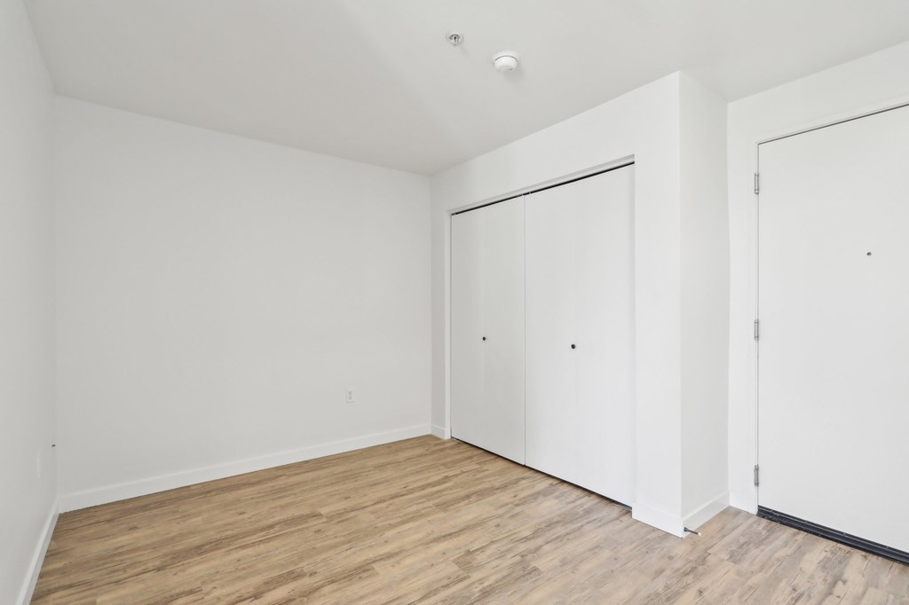 A room with white walls and wooden flooring with two doors.