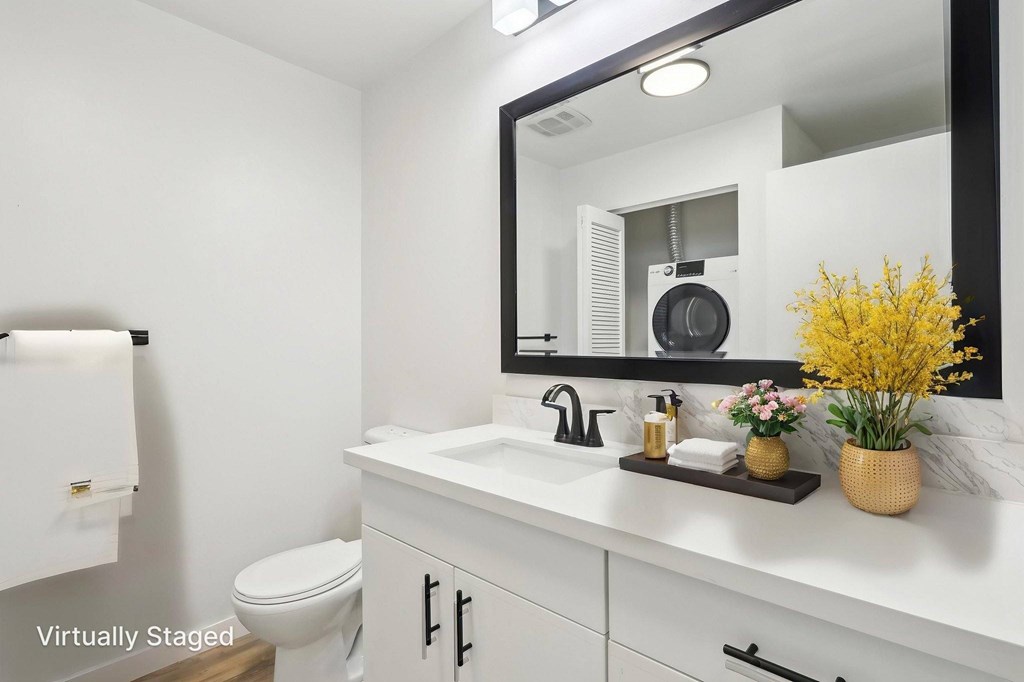 A white bathroom with a toilet, sink, and mirror.