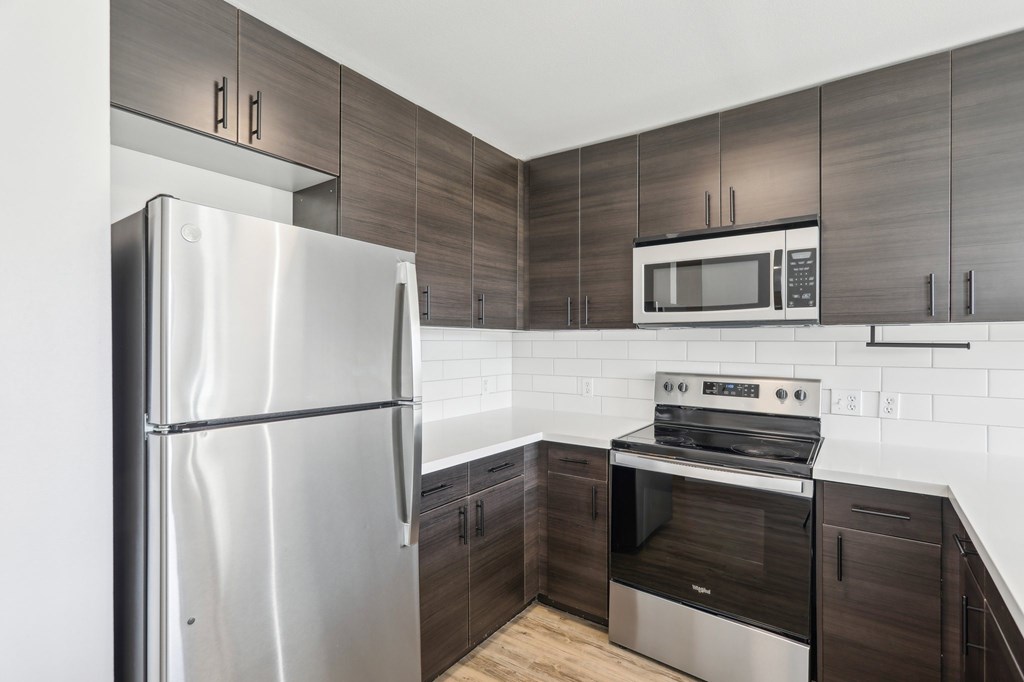 A modern kitchen with a stainless steel refrigerator, microwave, and oven.