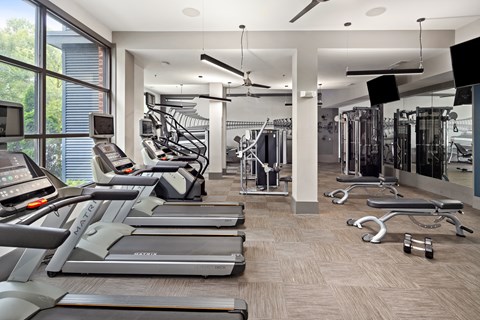 a gym with treadmills and other cardio equipment and a large window
