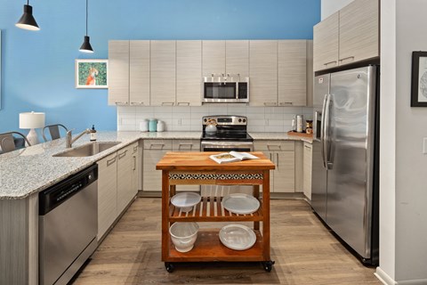 a kitchen with white cabinets and stainless steel appliances and a table with pots and pans