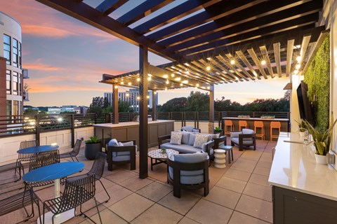 a rooftop patio with tables and chairs and a pergola at dusk