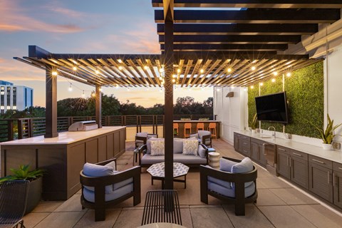 a rooftop patio with a bar and chairs and a tv