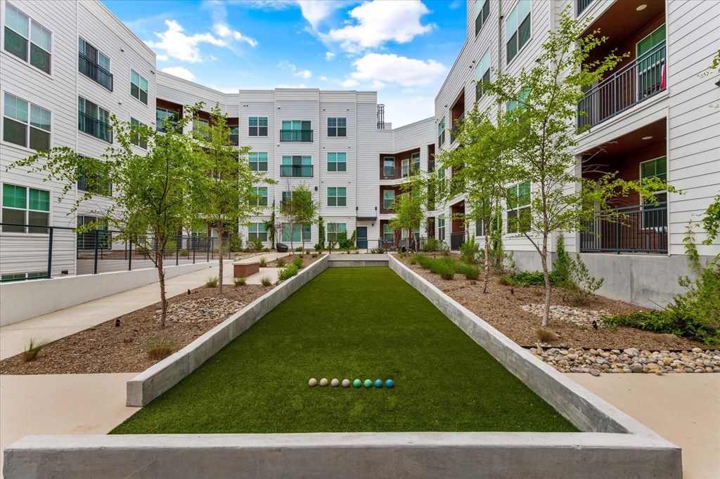 a grassy area with trees and buildings in the background