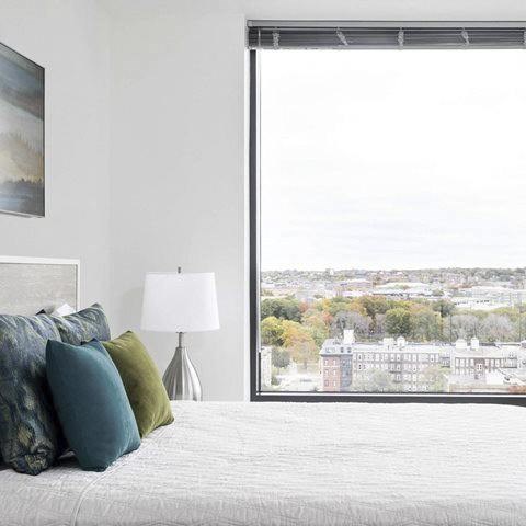 A bedroom with a large bed and a view of a cityscape through a window.