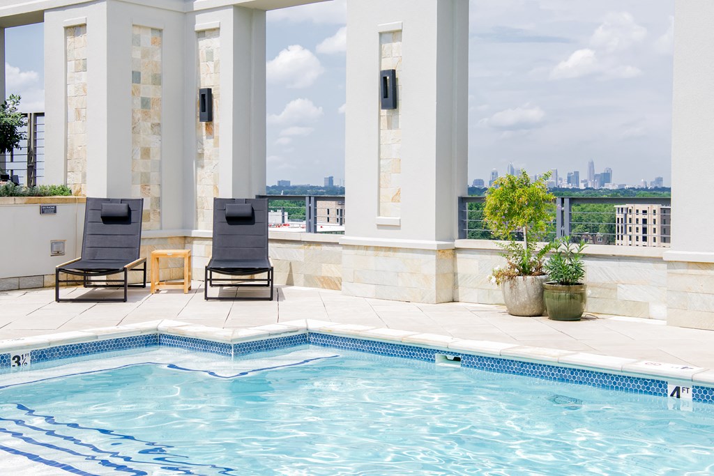 a swimming pool with two lounge chairs and a view of the city