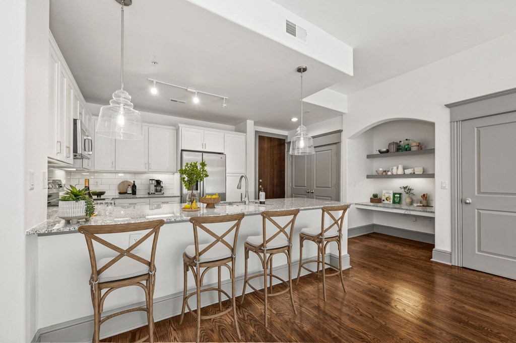 a kitchen with white cabinets and a marble counter top
