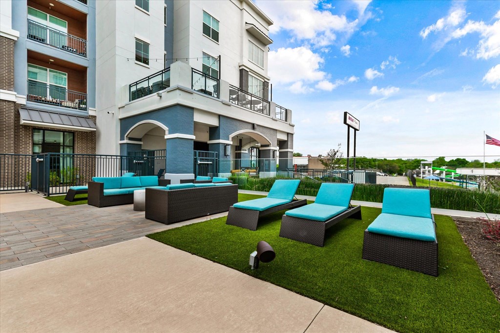 a patio with lounge chairs and a fire hydrant in front of an apartment building